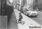 Girl on sidewalk upon tricycle