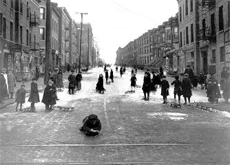 Street with little snow, many sledders